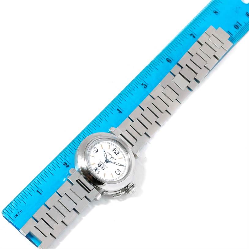 The image shows a Cartier Pasha W31044M7 Men
s Stainless Steel Silver Dial W31044M7 Men
s Stainless Steel Silver Dial watch laid flat with its bracelet strap aligned next to a blue ruler for measurement.