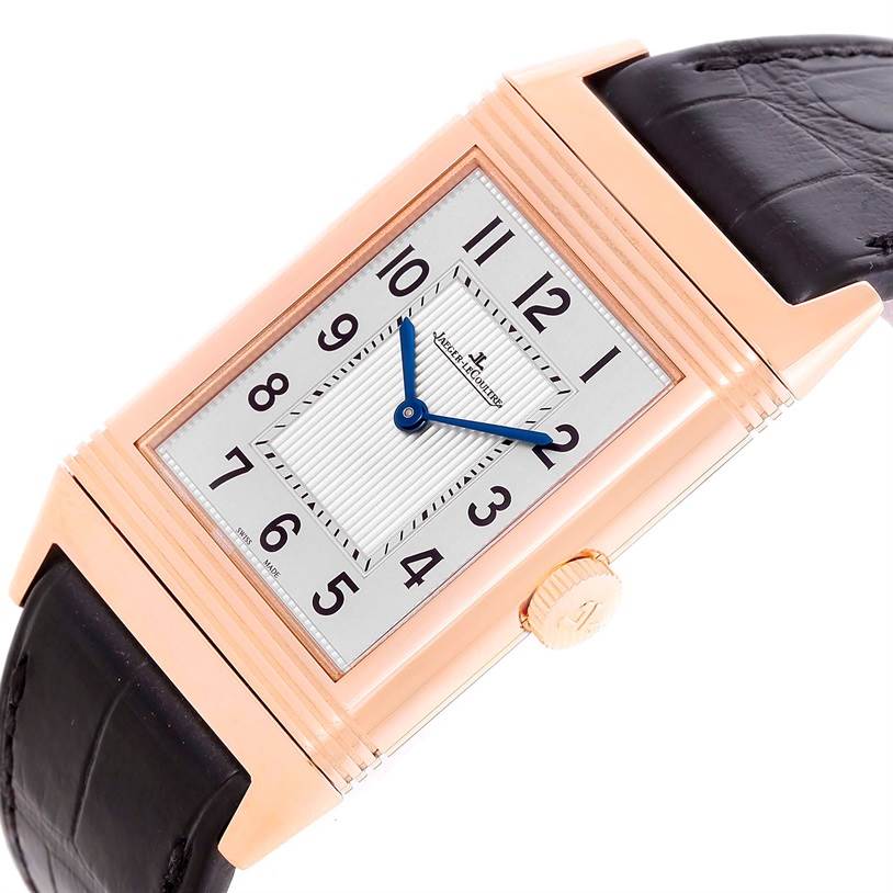 The image shows a close-up of the Jaeger-LeCoultre Reverso watch, highlighting its rectangular dial, gold case, blue hands, and black leather strap.