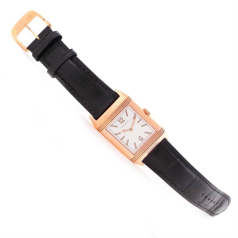 The image shows a Jaeger LeCoultre Reverso Q2782521 Men's Rose Gold White Dial Q2782521 Men's Rose Gold White Dial watch at a top-down angle, highlighting its face, black leather strap, and gold buckle.