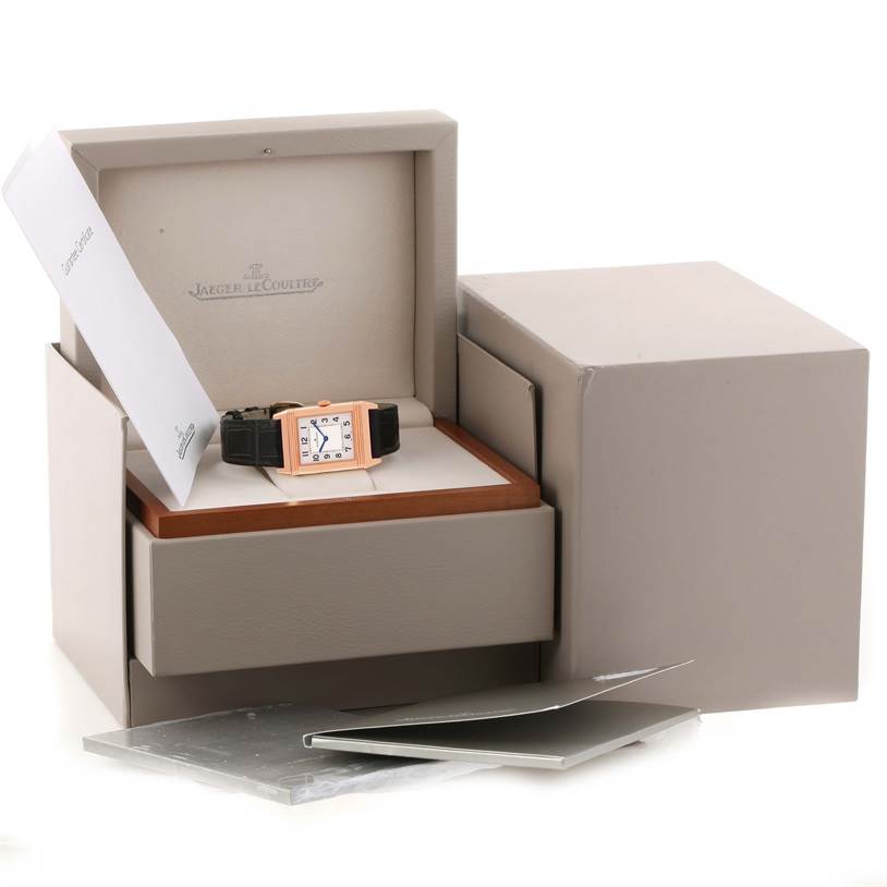 The image shows a Jaeger LeCoultre Reverso Q2782520 Men's Rose Gold Silver Dial Q2782520 Men's Rose Gold Silver Dial watch in an open box, with additional packaging and documents around it.