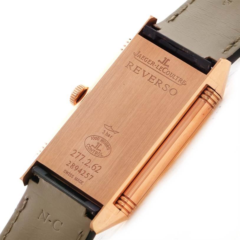The image shows the back case of the Jaeger-LeCoultre Reverso watch, featuring engravings and part of the strap.