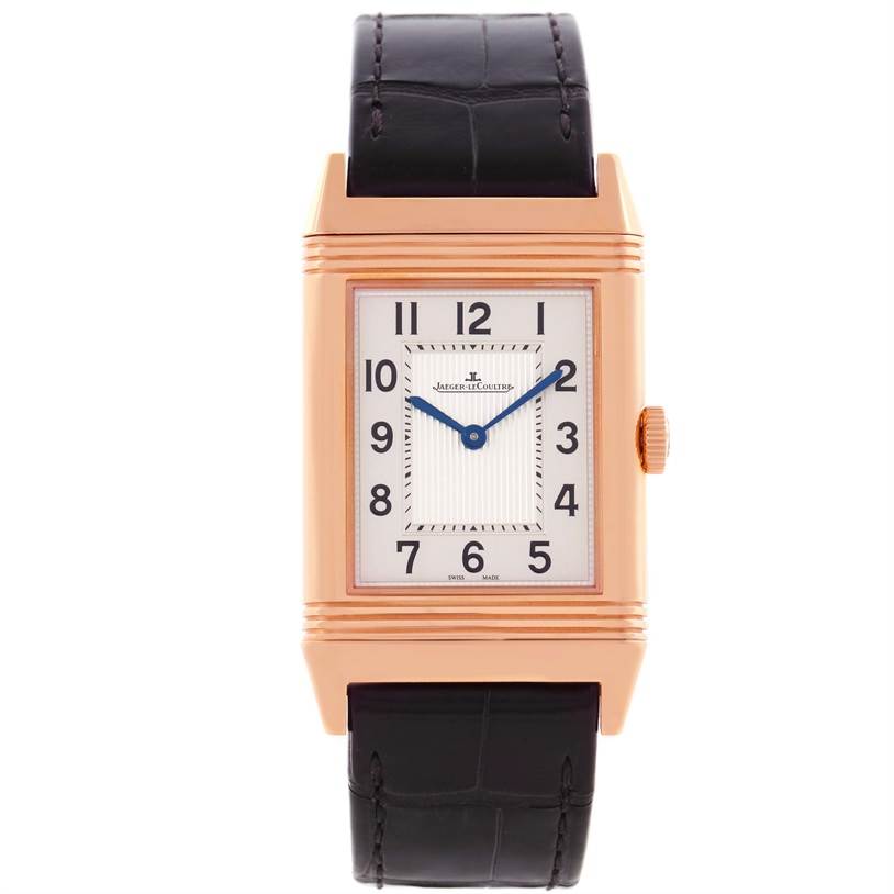 The image shows a front view of a Jaeger-LeCoultre Reverso watch, highlighting its rectangular gold case, dial, and black leather strap.