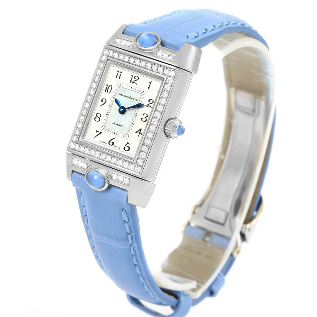 The image shows a front angle of a Jaeger-LeCoultre Reverso watch featuring a rectangular face, diamond bezel, and a blue strap.