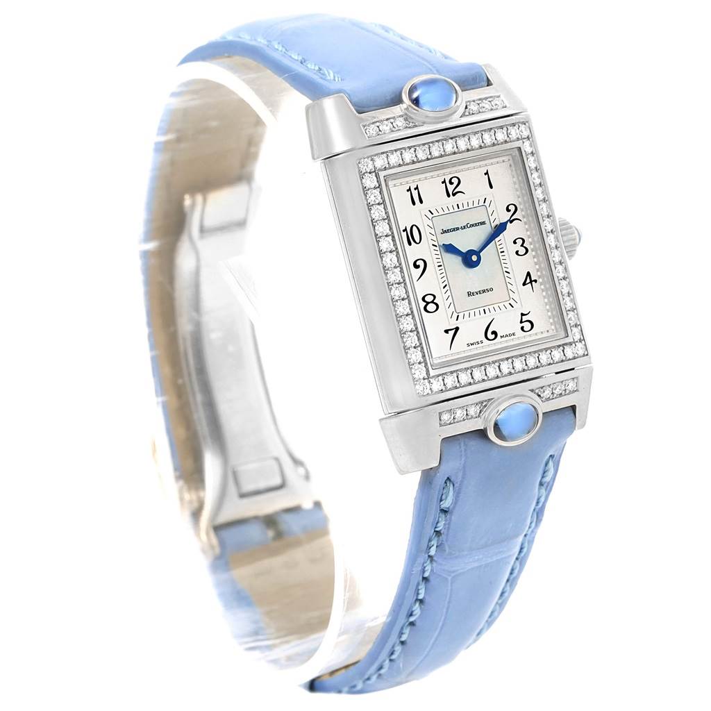 This image shows a Jaeger-LeCoultre Reverso watch at an angled front view, displaying its rectangular face, diamond bezel, and blue leather strap.