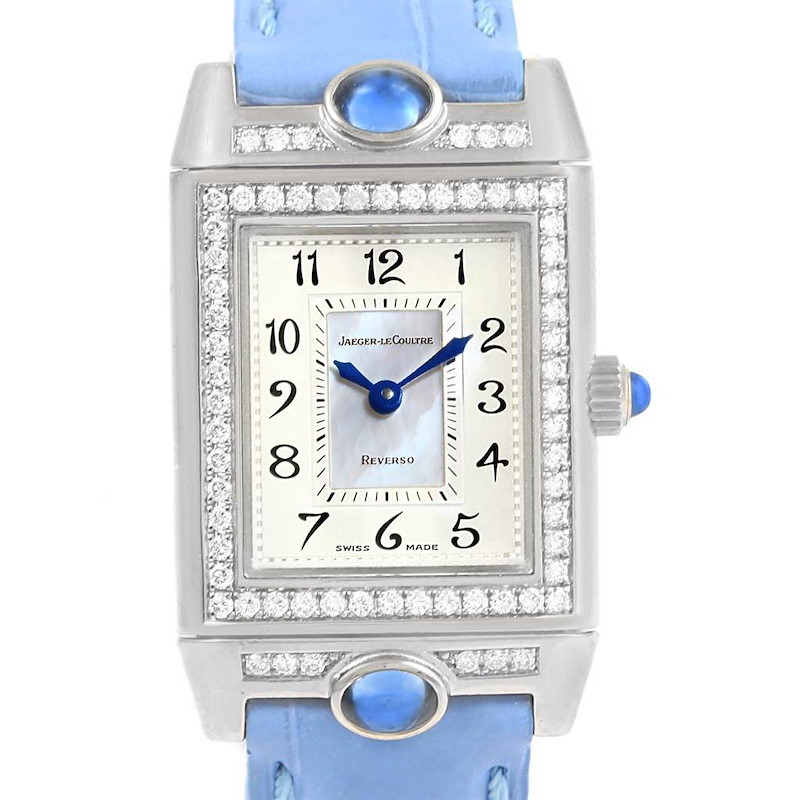 The Jaeger LeCoultre Reverso watch is shown from a front angle, highlighting its face, bezel, blue strap, and crown.