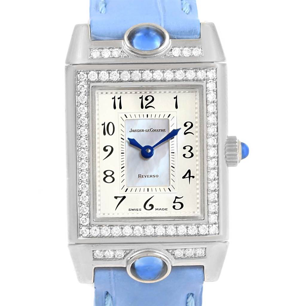 The Jaeger LeCoultre Reverso Q2623402 Women's White Gold Mother of Pearl Dial Q2623402 Women's White Gold Mother of Pearl Dial watch is shown from a front angle, highlighting its face, bezel, blue strap, and crown.