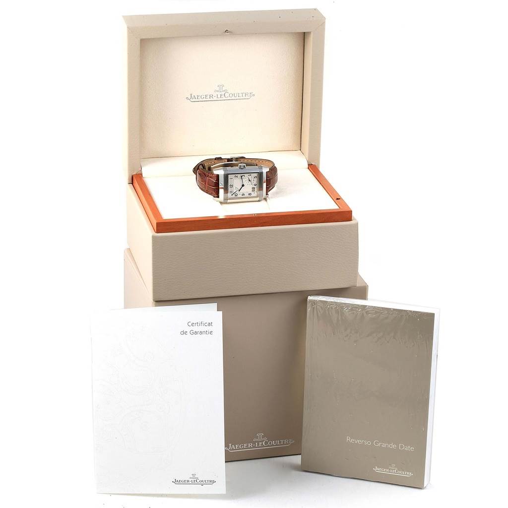 The image shows a Jaeger-LeCoultre Reverso watch in its box at a front angle, with warranty certificate and manual.