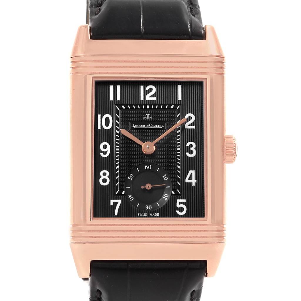 The image shows a frontal view of a Jaeger LeCoultre Reverso Q3732470 Men's Rose Gold Black Dial Q3732470 Men's Rose Gold Black Dial watch with a black strap and a rectangular gold-toned case.