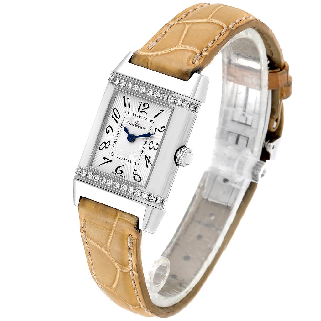 The image shows a Jaeger-LeCoultre Reverso watch at an angle highlighting the face, crown, and tan leather strap.