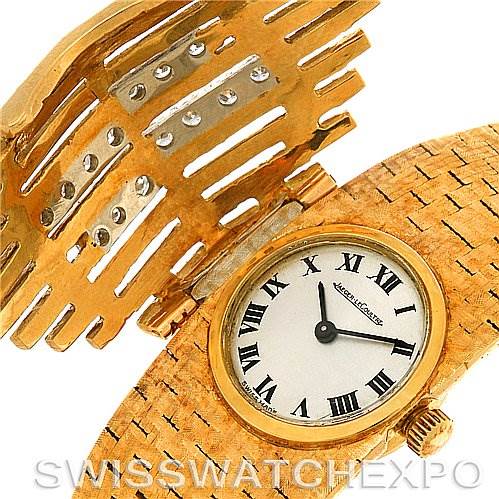 This image shows a close-up of a Jaeger LeCoultre Vintage Women
s Yellow Gold Silver Dial Women
s Yellow Gold Silver Dial model watch with the open golden cover revealing its dial.