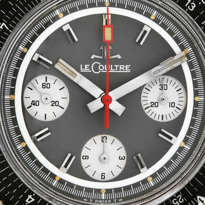This close-up shows the dial of a Vintage Jaeger LeCoultre watch, featuring sub-dials and a prominent red second hand.
