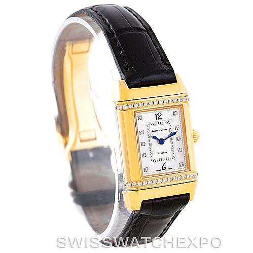 The image shows a frontal view of a Jaeger-LeCoultre Reverso watch with a gold case, leather strap, and diamond accents.