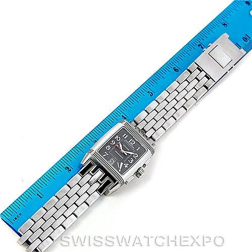 The image shows a Jaeger-LeCoultre Reverso watch laid flat next to a ruler, displaying its face, bezel, and metal bracelet.