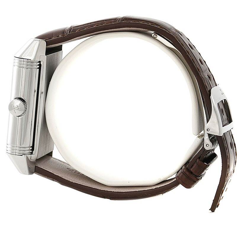 The image shows a side view of the Reverso watch by Jaeger LeCoultre, highlighting its rectangular case, crown, and brown leather strap.