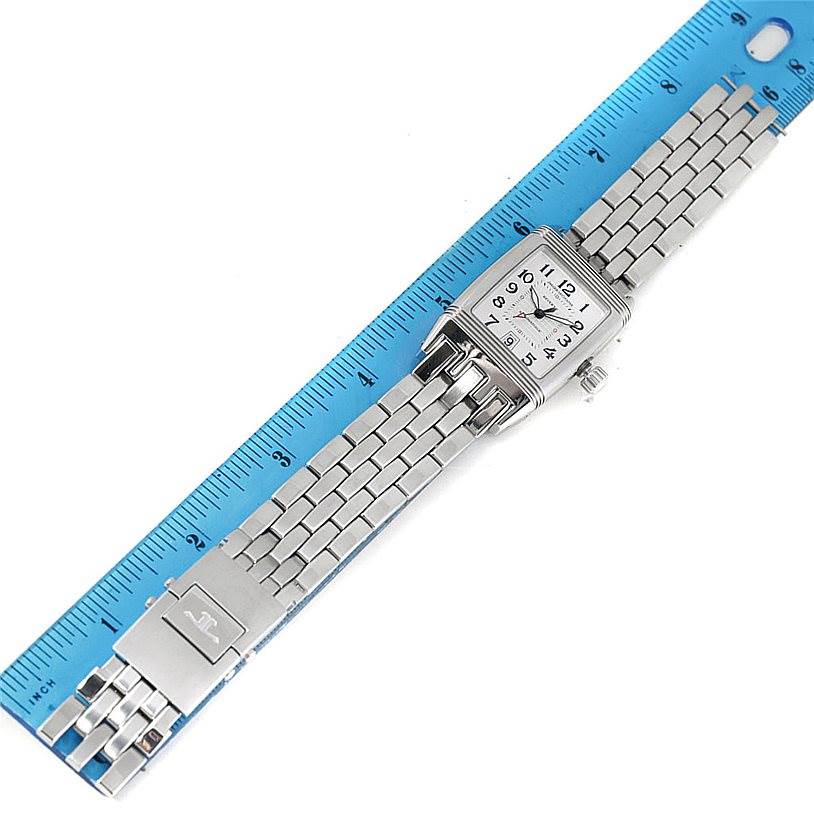 The Reverso model by Jaeger LeCoultre is shown from a top-down angle, displaying its face, metal bracelet, and deployment clasp, with a ruler for scale.