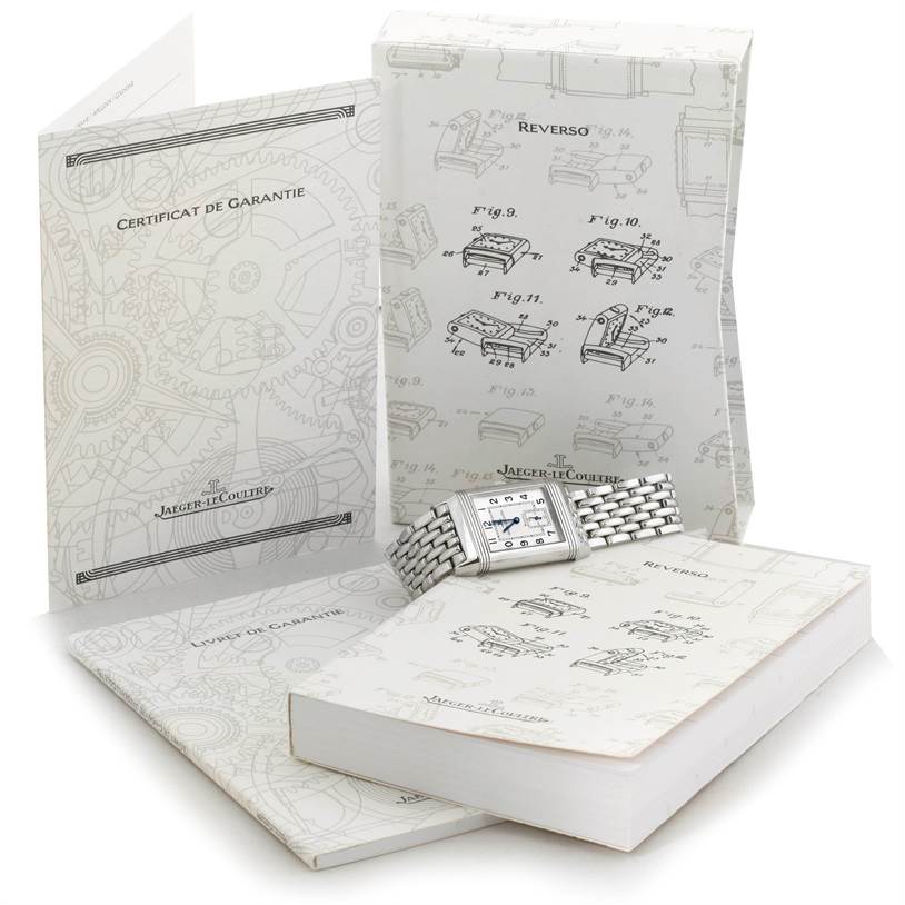 The Jaeger LeCoultre Reverso 270.8.62 Men's Stainless Steel Silver Dial 270.8.62 Men's Stainless Steel Silver Dial watch is displayed flat, accompanied by warranty and instruction booklets in the background.