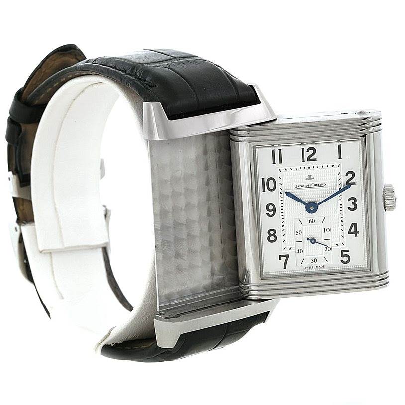 The image shows a Jaeger-LeCoultre Reverso watch with its case reversed, displaying the back and highlighting the black leather strap.