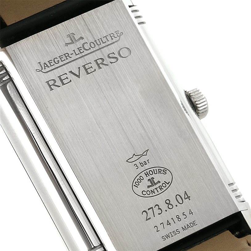 The image shows the back case of a Jaeger-LeCoultre Reverso watch, featuring its inscriptions and crown on the side.