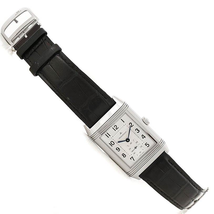 The image shows a Jaeger-LeCoultre Reverso watch angled diagonally, displaying the face, case, crown, and black leather strap.