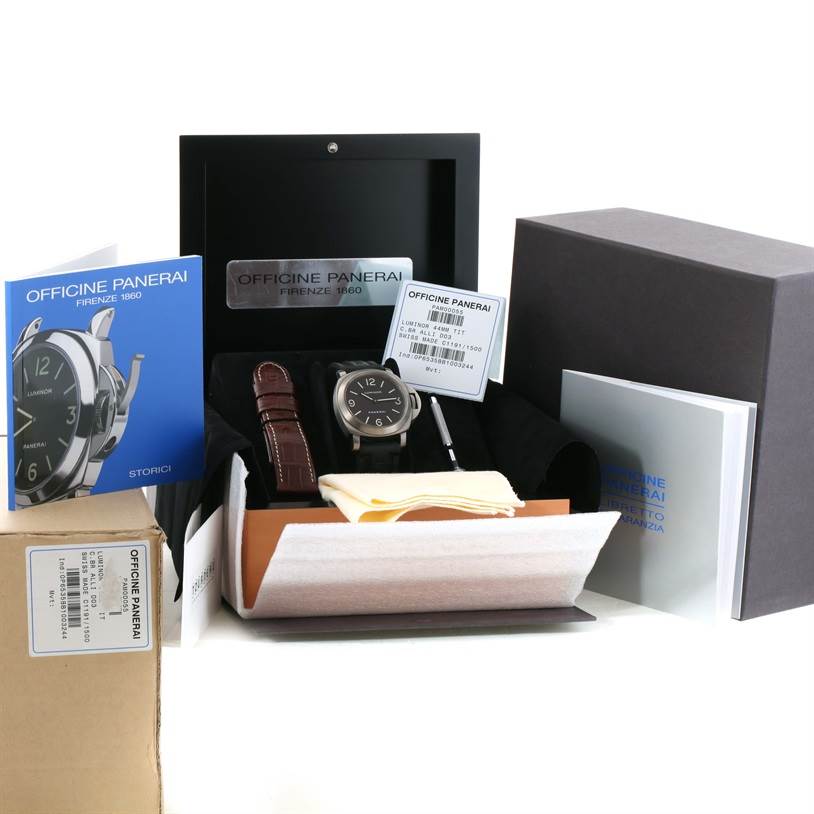 The image shows a Panerai Luminor PAM00055 Men
s Titanium Black Dial PAM00055 Men
s Titanium Black Dial watch from a front angle, along with its packaging, a brown leather strap, manuals, and an additional tool.