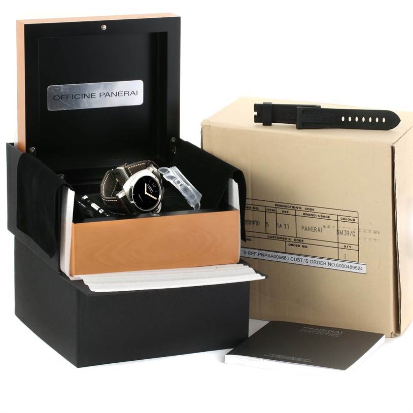 The image shows a Panerai Luminor PAM00351 Men
s Titanium Brown Dial PAM00351 Men
s Titanium Brown Dial watch in an open case with additional packaging and a spare strap.