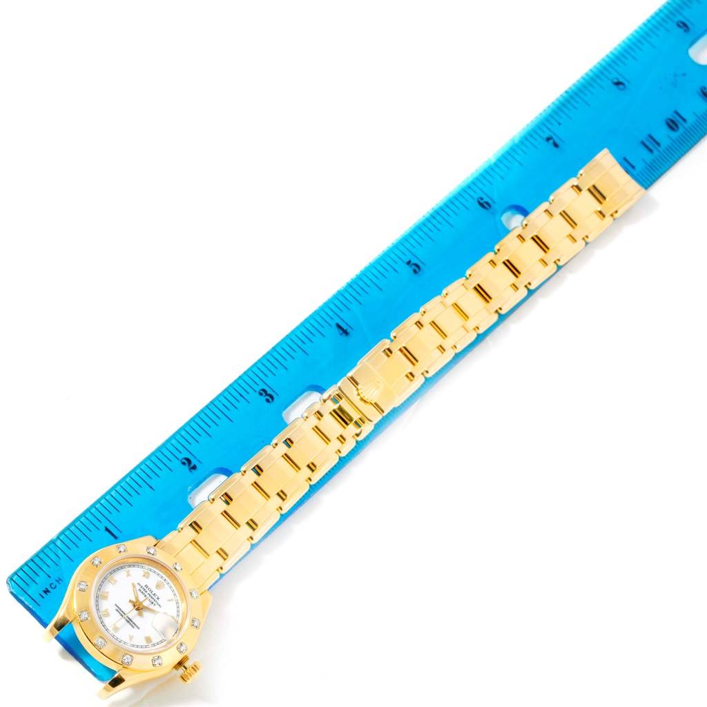 The Rolex Pearlmaster 69318 Women's Yellow Gold White Dial 69318 Women's Yellow Gold White Dial watch is shown laying flat with the face, bracelet, and part of a blue ruler visible.