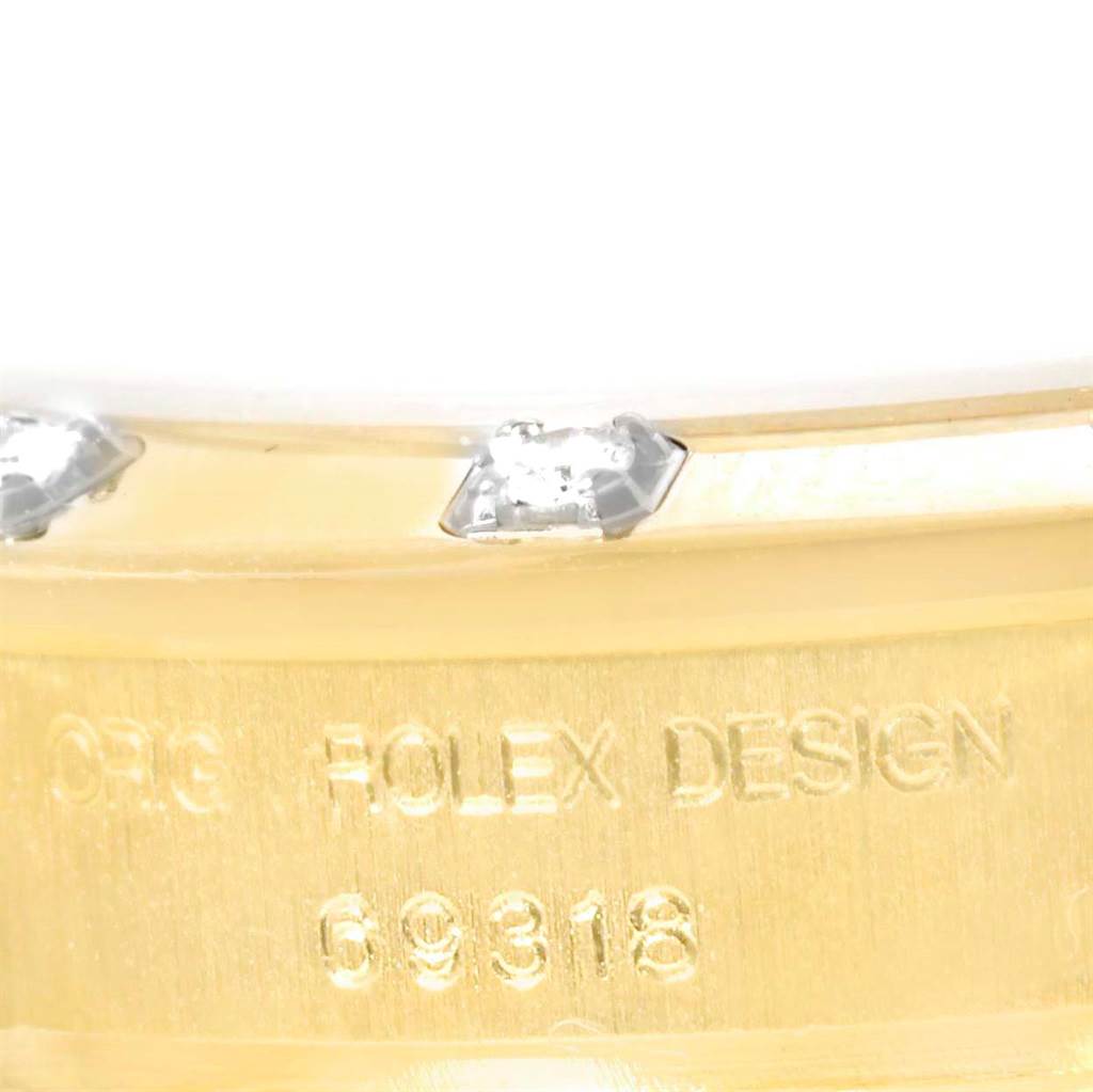 This image shows a close-up of the side of a Rolex Pearlmaster 69318 Women's Yellow Gold White Dial 69318 Women's Yellow Gold White Dial watch case, highlighting its diamond accents and engraved design number.