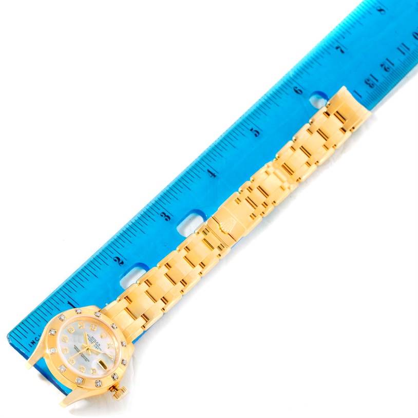 The image shows a Rolex Pearlmaster 80318 Women's Yellow Gold Mother of Pearl Dial 80318 Women's Yellow Gold Mother of Pearl Dial watch placed parallel to a blue ruler, displaying the watch face and full bracelet.