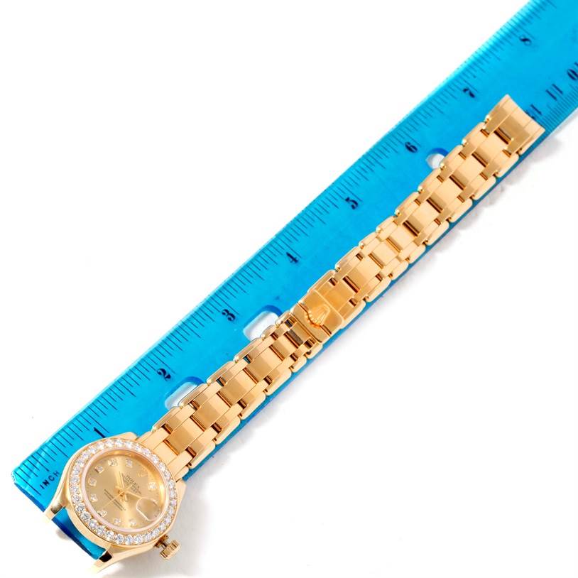 The image shows a Rolex Pearlmaster 69298 Women's Yellow Gold Champagne Dial 69298 Women's Yellow Gold Champagne Dial watch laid flat next to a blue ruler, displaying its gold bracelet and diamond bezel.