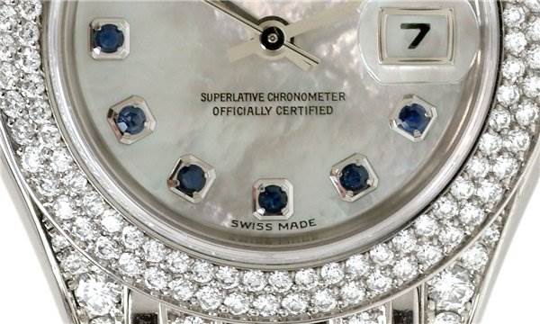 The image shows a close-up of the Rolex Pearlmaster 80359 Women's White Gold Mother of Pearl Dial 80359 Women's White Gold Mother of Pearl Dial watch face, highlighting the gemstone hour markers and diamond-encrusted bezel.