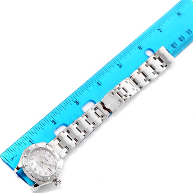 The Rolex Pearlmaster 80319 Women's White Gold Mother of Pearl Dial 80319 Women's White Gold Mother of Pearl Dial watch is shown from a top-down angle, highlighting the bracelet, clasp, and face next to a blue ruler for scale.