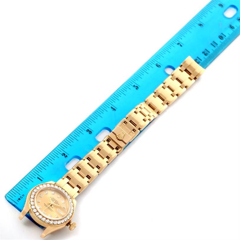 This image shows the Rolex Pearlmaster 80298 Women's Yellow Gold Champagne Dial 80298 Women's Yellow Gold Champagne Dial watch from a top-down angle, highlighting the face, bezel, bracelet, and clasp next to a ruler.