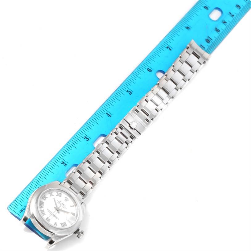 The Rolex Pearlmaster 81209 Women's White Gold White Dial 81209 Women's White Gold White Dial watch is shown from a top view, showcasing the full watch band and watch face next to a blue ruler.