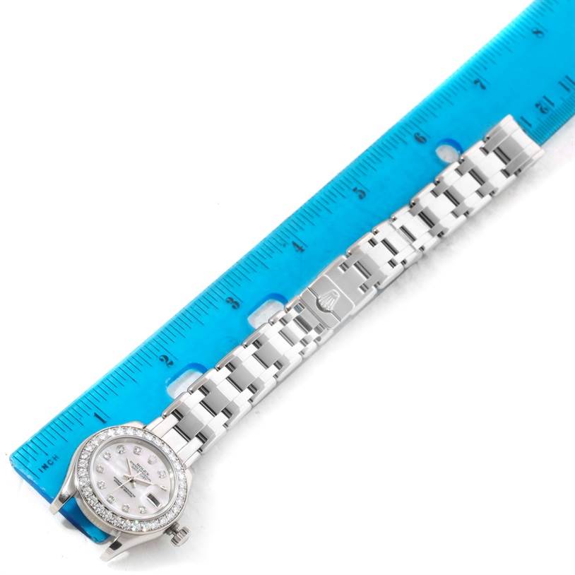 The image shows a Rolex Pearlmaster 80299 Women's White Gold Mother of Pearl Dial 80299 Women's White Gold Mother of Pearl Dial watch laying flat, with a focus on its band and bezel, next to a blue ruler for scale.