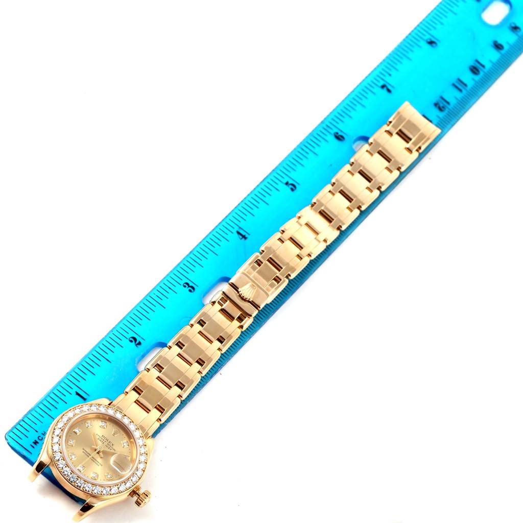 This image shows the full front view of a Rolex Pearlmaster 69298 Women's Yellow Gold Champagne Dial 69298 Women's Yellow Gold Champagne Dial watch placed alongside a blue ruler.