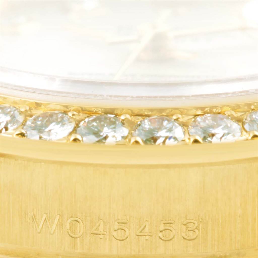 This image shows the bezel with diamonds and part of the gold case of a Rolex Pearlmaster 69298 Women's Yellow Gold Silver Dial 69298 Women's Yellow Gold Silver Dial model watch.