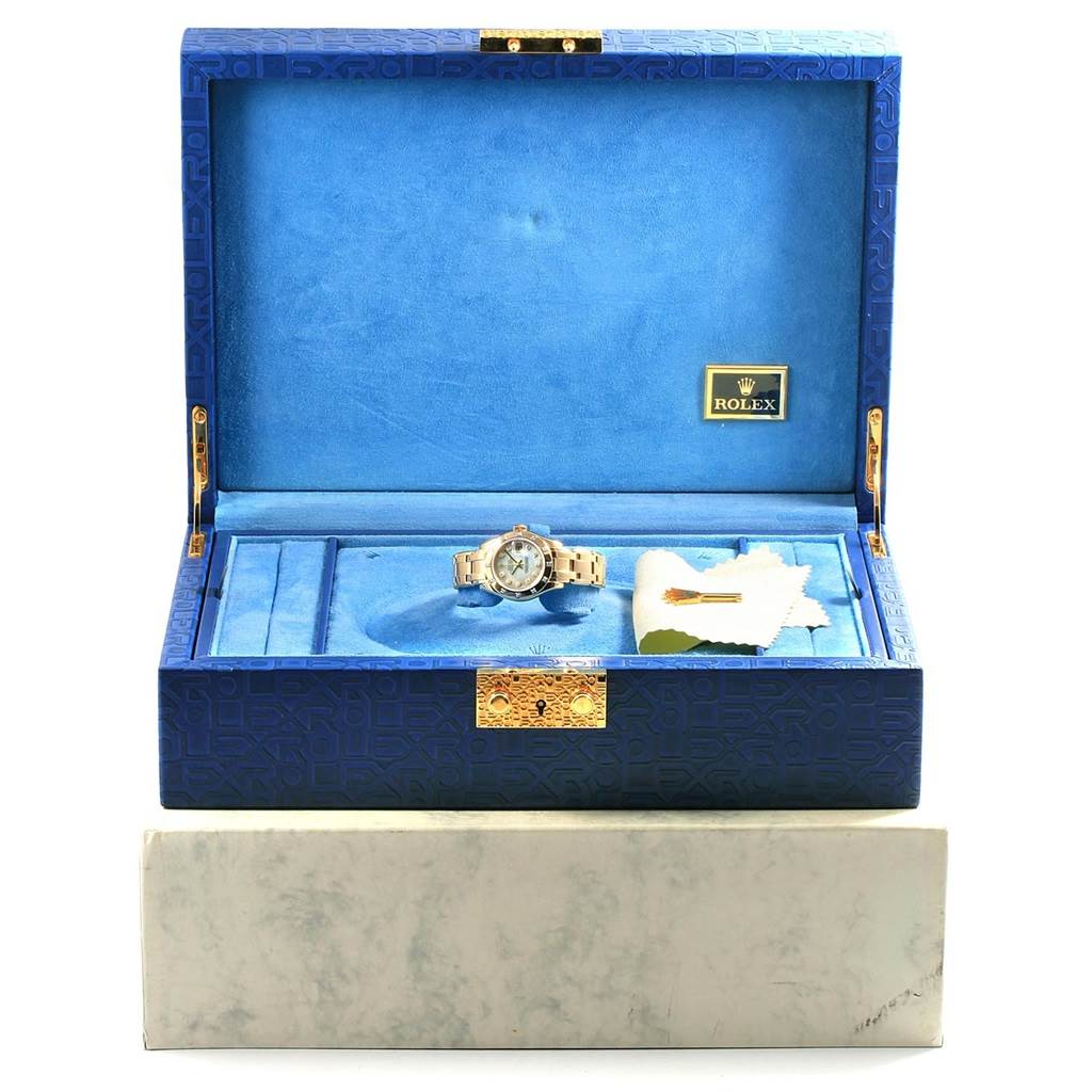 The image shows a Rolex Pearlmaster 80318 Men's Yellow Gold Mother of Pearl Dial 80318 Men's Yellow Gold Mother of Pearl Dial watch in an open blue display box, including a cleaning cloth and a golden key.