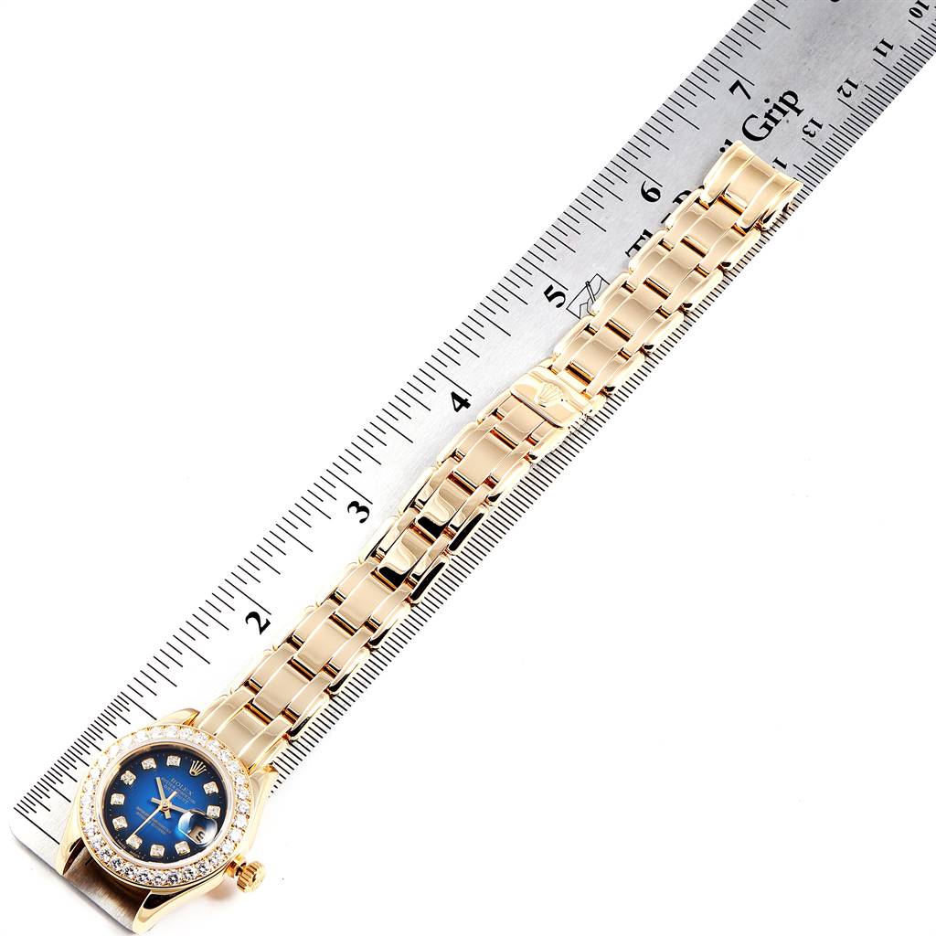 The Rolex Pearlmaster 69298 Women's Yellow Gold Blue Dial 69298 Women's Yellow Gold Blue Dial watch is shown from the side, featuring its dial, bezel with diamonds, and bracelet against a ruler for scale.