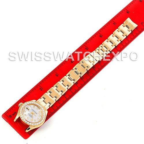 The Rolex Pearlmaster 802998 Women's Yellow Gold Mother of Pearl Dial 802998 Women's Yellow Gold Mother of Pearl Dial watch is shown from a top-down angle, fully extended next to a red ruler for scale.