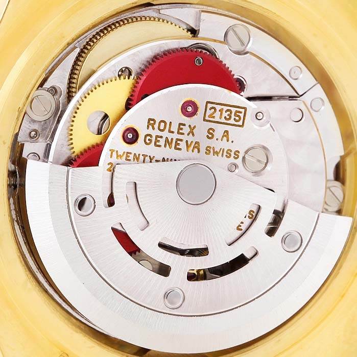 A close-up view of the internal mechanical movement of the Rolex Pearlmaster 69308 Women's Yellow Gold  69308 Women's Yellow Gold  model, displaying gears and inscriptions.